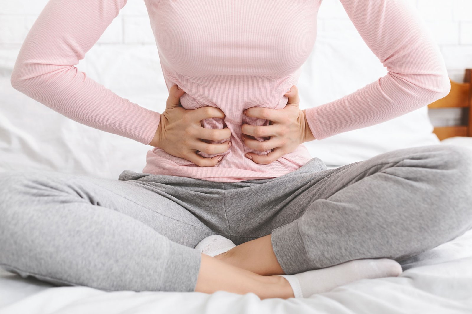Woman holding lower abdomen due to stomach pain and digestive discomfort